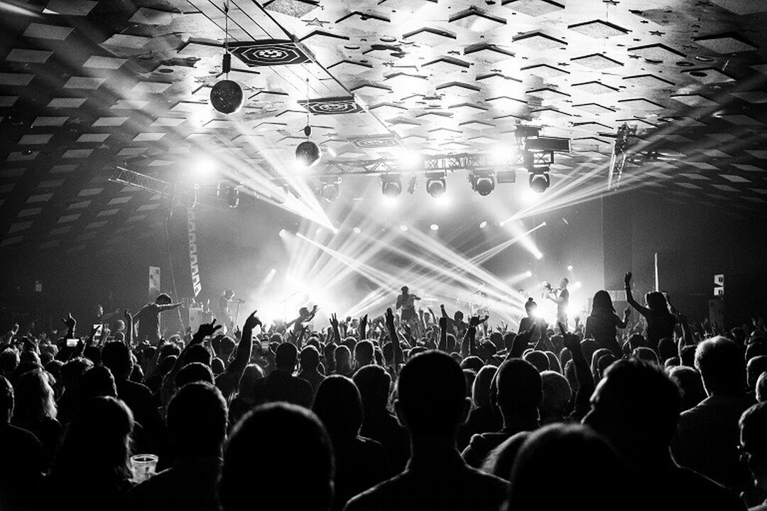 A crowd enjoying a performance at Glasgow's Barrowland Ballroom. The picture is in black and white with strobe lights.