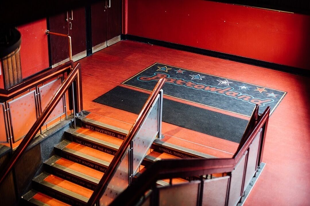Red flooring at the top of a staircase inside Glasgow's Barrowland Ballroom that reads 'Barrowland'.