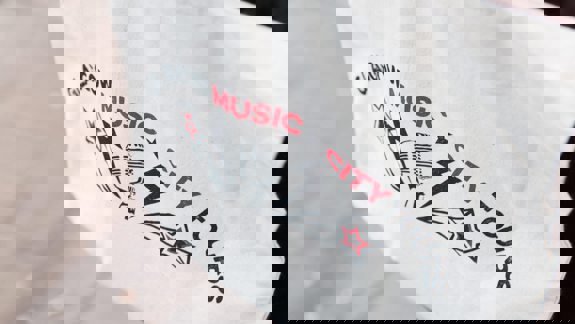 A close-up of a white tote bag with "Glasgow Music City Tours" and a microphone logo.