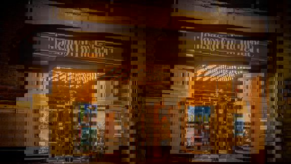 The illuminated entrance of the historic Glasgow Film Theatre at night, with movie posters displayed and a person walking in, under its classic marquee.