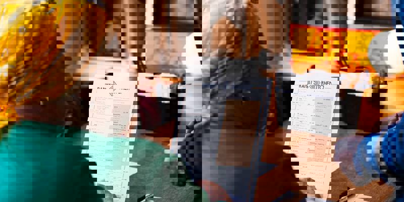 A person with a yellow headscarf reads a menu at Ranjit's Kitchen, a restaurant with a friendly atmosphere.