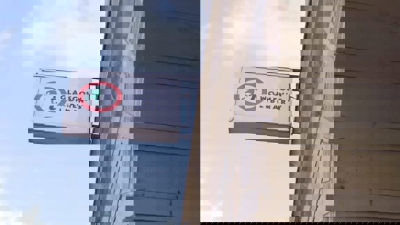 A white sign with a red circle logo and "Glasgow Women's Library" hangs from a stone building.