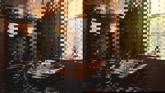 The kitchen of the Tenement House, preserved as it was, with an old black stove, drying laundry overhead, and period furnishings, lit by a large window.