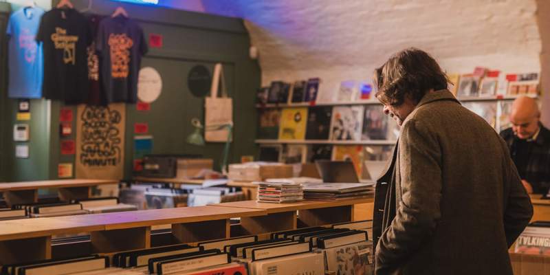 A man browses records in Monorail Music, a brightly lit record store with shelves filled with vinyl albums.