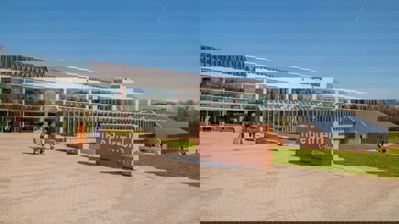 The exterior of The Burrell Collection in Glasgow. A sign reading 'The Burrell Collection' stands in front of the museum with trees behind.