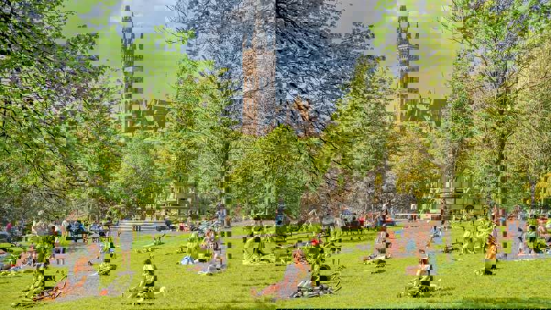 Kelvingrove Park: A park with people relaxing on the grass on a sunny day, with the University of Glasgow building visible in the background.