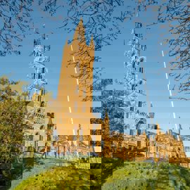 A beautiful view of the University of Glasgow's main building, a striking gothic-style tower with a tall spire, on a sunny day.