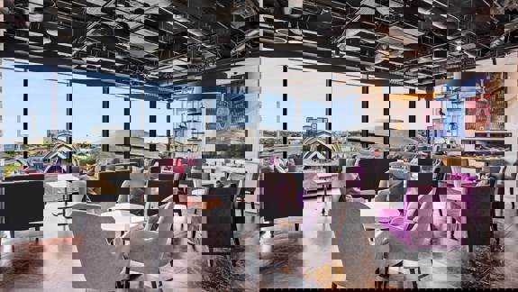 Chic Sky Bar at Radisson RED Glasgow with floor-to-ceiling windows, plush seating in purple and grey tones, and panoramic views over the Clyde and SEC Armadillo.