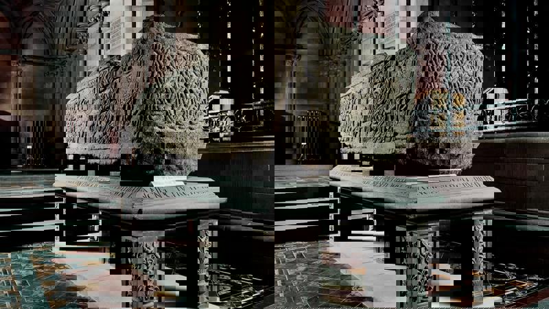 An ancient carved stone sarcophagus, known as one of the Govan Stones, is on display inside a historic church.