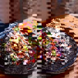 A beautifully presented dish of food at Ocho, a Glasgow restaurant, featuring a fried egg, avocado, and other toppings on a dark plate.