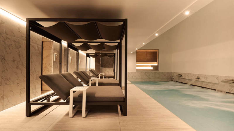 Luxurious spa at Kimpton Blythswood Square Hotel with a serene vitality pool, lounge beds, marble walls, and soft ambient lighting.