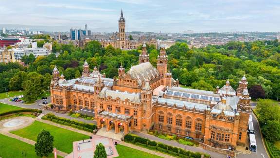 An aerial view of the grand, red sandstone Kelvingrove Art Gallery and Museum set within large green parklands.