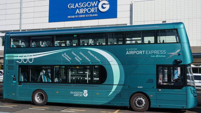 A turquoise First Bus double-decker bus for the Glasgow Airport Express 500 service parked in front of the main terminal building at Glasgow Airport.