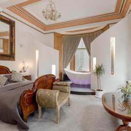 Elegant bedroom at The Alamo Guest House featuring a wooden sleigh bed, freestanding bathtub with mood lighting, and classic décor with ornate furnishings.